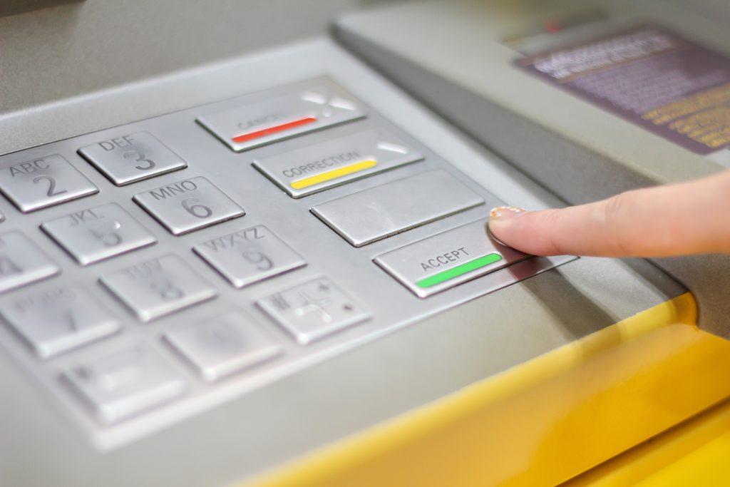 Someone interacting with an ATM keypad showing the raised areas of keys.