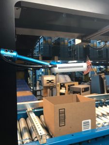 Intel RealSense depth camera scanning the contents of a box on a conveyor belt